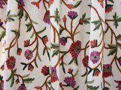 an embroidered curtain with flowers and leaves on it