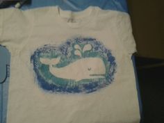 a white t - shirt with a blue whale on the front and green whales on the back