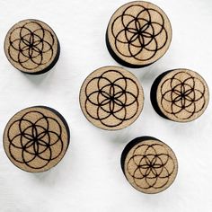 four wooden knobs with designs on them sitting on a white table top next to each other