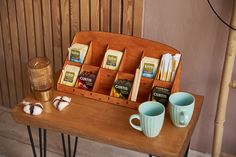 a wooden table topped with two cups filled with different types of teas and coffee beans