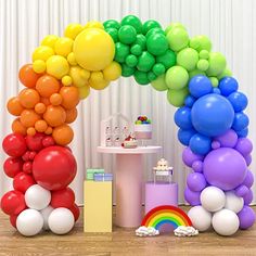 there is a rainbow balloon arch on the floor