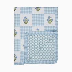 a blue and white checkered baby blanket with flowers on it's side, in front of a white background