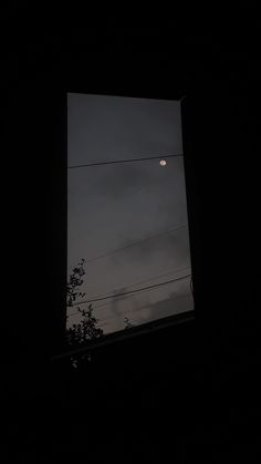 the moon is seen through an open window at night, with power lines in the distance