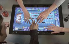 three people are playing a game on a large tablet screen while holding their hands together