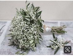 two bouquets of white flowers are on a table with an old - fashioned bottle