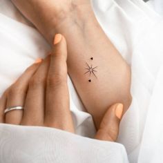 a woman's arm with a small star tattoo on it