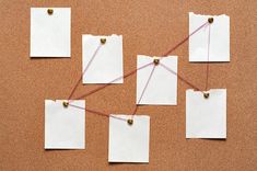 four pieces of paper with pins and string attached to them on a cork bulletin board