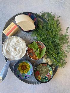 an assortment of food on a plate with spoons and bowls filled with dip sauce