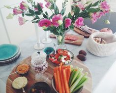 a table topped with plates and bowls filled with food next to vases full of flowers