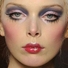 a woman with blue and pink makeup is looking at the camera