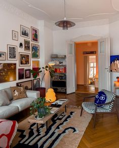 a living room filled with lots of furniture and pictures on the wall above it's doorway