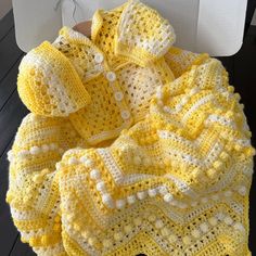 a crocheted yellow blanket with white trim