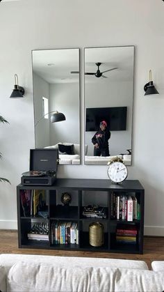 a living room with a couch, mirror and bookshelf in front of it