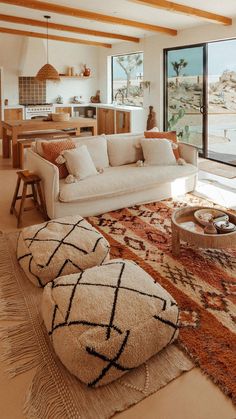 a living room filled with lots of furniture and large windows overlooking the water in front of it