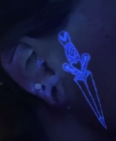 a woman with blue glow on her face and nose is looking at something in the dark