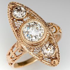 an antique diamond ring with three stones in the center and filigrees on each side