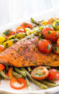 salmon with tomatoes and green beans on a white plate