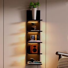 a shelf with books and plants on it in a corner next to a wall mounted speaker