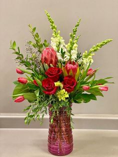 a vase filled with red and white flowers on top of a table next to a wall