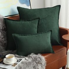 three green pillows on a couch with a cup of coffee