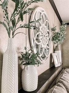 two white vases with green plants in them on a shelf next to a couch