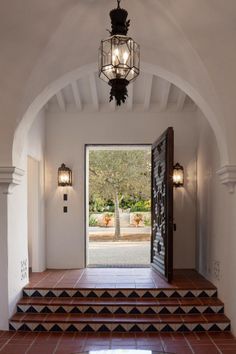 an entry way with steps leading up to the front door and light fixture hanging from the ceiling