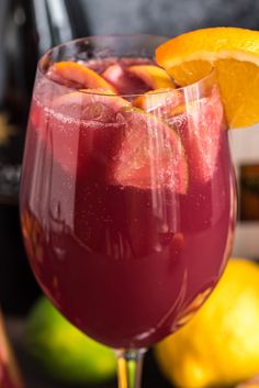 a close up of a wine glass filled with liquid and orange wedges on the side