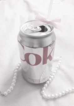 a can of coke is tied to a white beaded necklace on a bed sheet