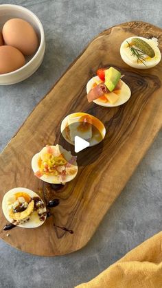 a wooden platter filled with deviled eggs and other food on top of a table