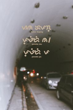 cars are parked on the side of a road under an overpass with words written in cursive writing