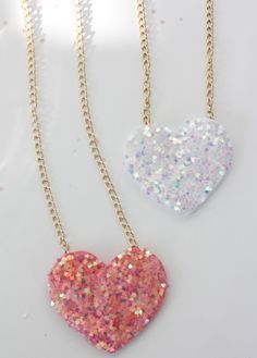 two heart shaped necklaces with glitter on them