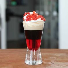 there is a drink with whipped cream and strawberries in the glass on the table