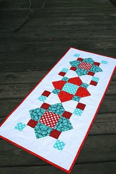 a quilted table runner with red, white and blue stars on it sitting on a wooden deck