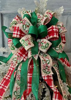 a red and green christmas bow on top of a tree