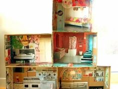 a doll house made out of cardboard boxes on top of a wooden floor next to a window