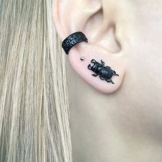 a woman's ear is decorated with black scorpions