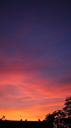 the sun is setting over some buildings and trees