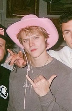 three young men wearing pink hats posing for the camera with one pointing at the camera