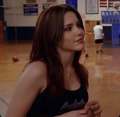 a beautiful young woman standing in front of a basketball court