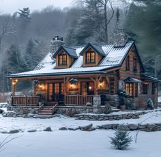 a log cabin in the snow with lights on