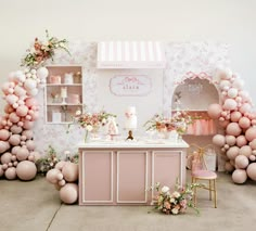 a pink and white dessert bar with balloons on the wall, flowers in vases