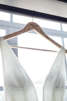 a white dress hanging on a wooden hanger