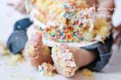 a baby with sprinkles on it's head is sitting in front of a cake