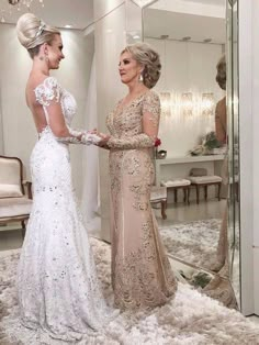 two women standing in front of a mirror and one is wearing a dress with lace on it