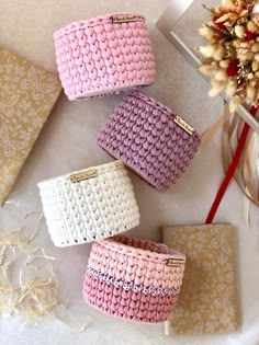 three small crocheted baskets sitting on top of a table next to a vase