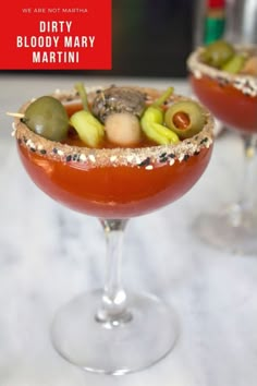 two martinis with olives, tomatoes and other toppings on the rim are ready to be served