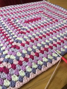 a crocheted blanket is laying on the floor next to a pair of scissors