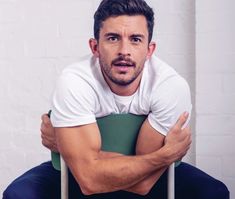 a man is sitting on a chair with his arms crossed and looking at the camera