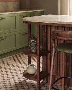 a kitchen with green cabinets and a marble counter top in front of a checkered floor