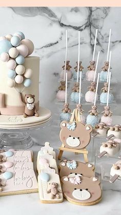 a table topped with cakes and cookies covered in icing next to cupcakes